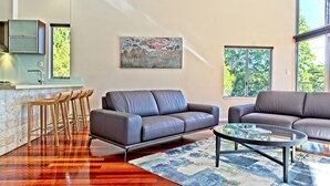 A modern living room with a sofa, coffee table, and bar stools.