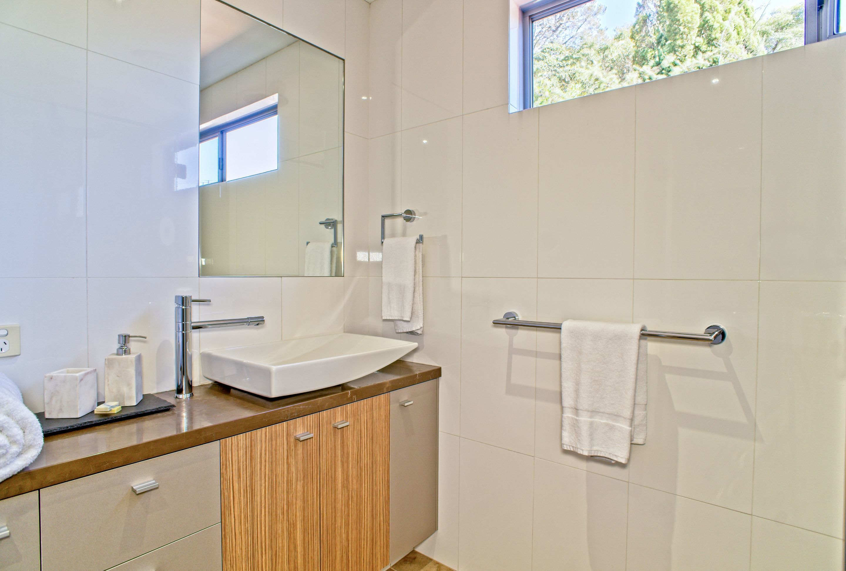 A modern bathroom with a large mirror, a sink, and a towel rack.