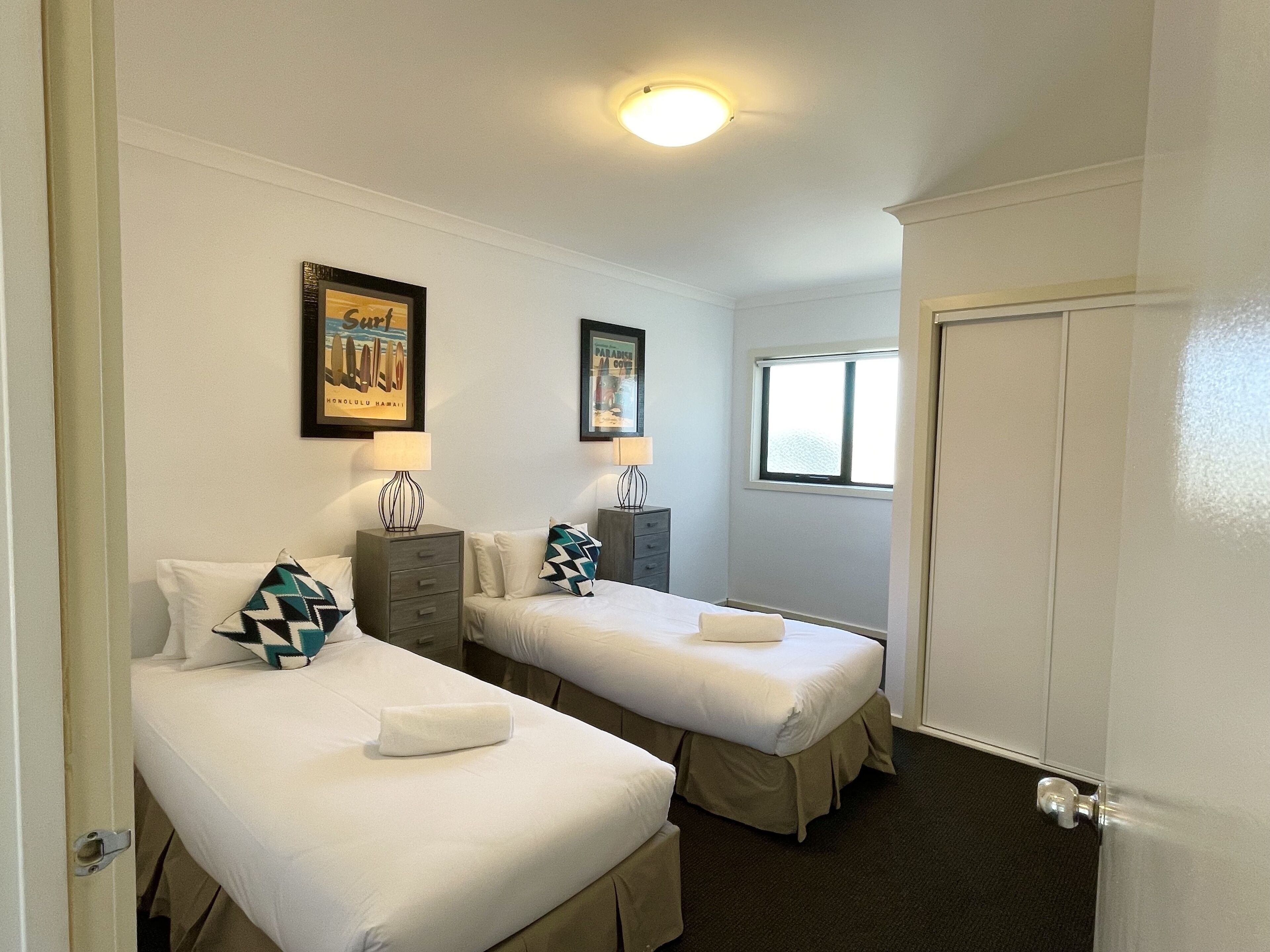Una habitación de hotel con dos camas, una ventana y una puerta.