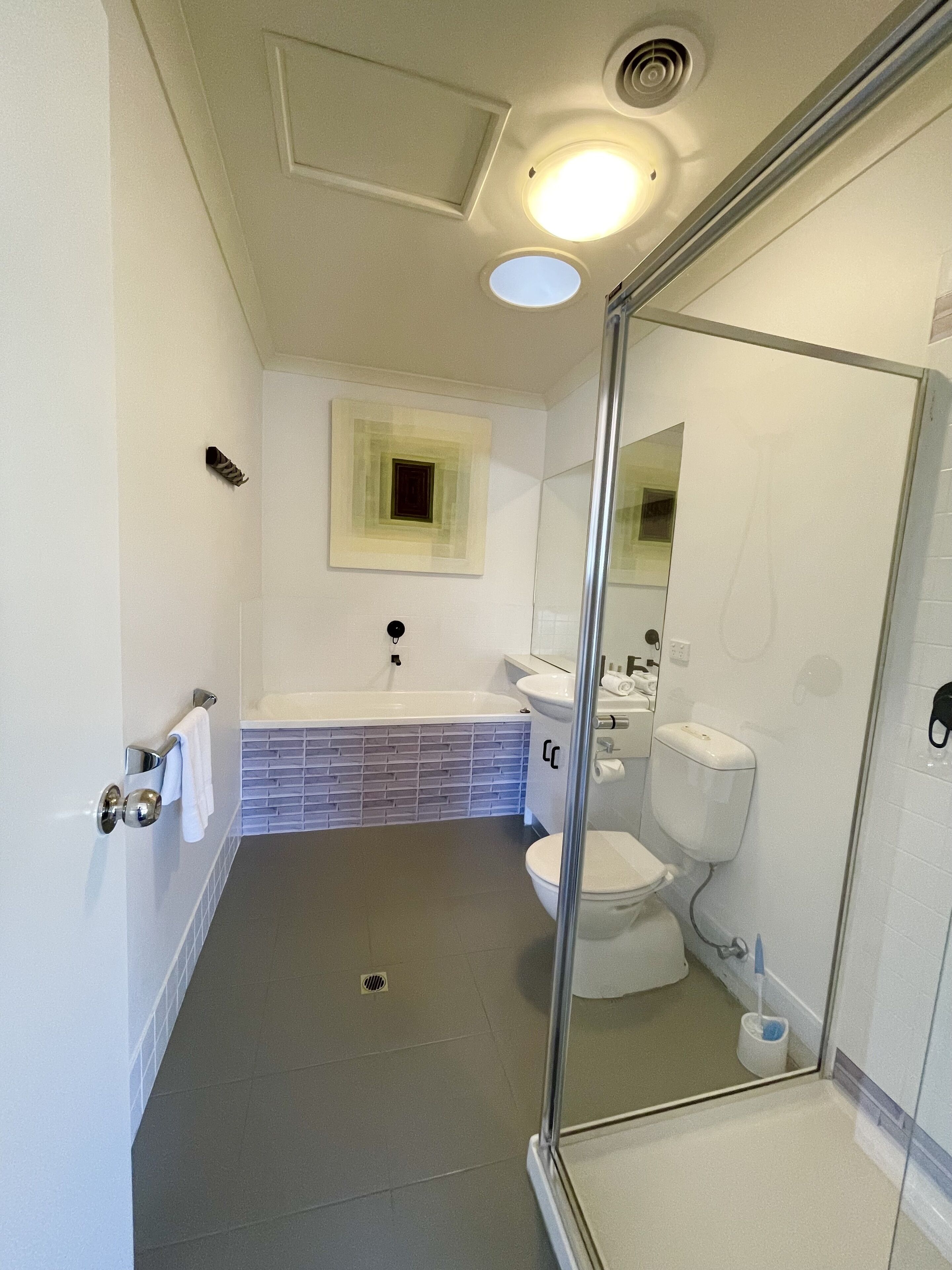 A modern bathroom with a glass shower enclosure, a white bathtub, and a toilet.
