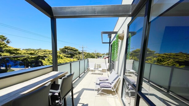 A balcony with a dining area, chairs, and a table. - Oceanic On Thompson Apartments (Cowes)