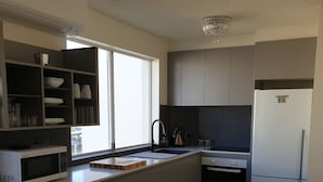 A modern kitchen with a central island, built-in appliances, and a large window providing natural light.