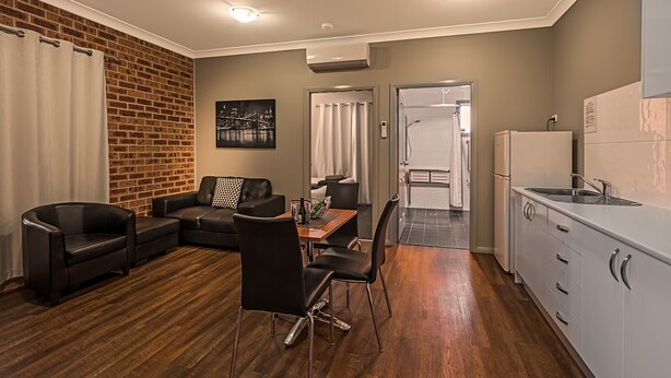 A modern apartment with a dining area, kitchen, and living room. - Akuna Motor Inn and Apartments (Dubbo)