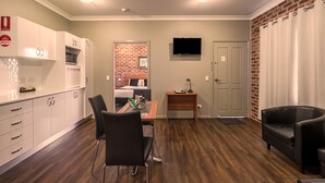 A compact living space with a kitchen, dining area, and a small bedroom. - Akuna Motor Inn and Apartments (Dubbo)