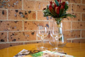 A table with two empty wine glasses and a vase with red flowers. - Akuna Motor Inn and Apartments (Dubbo)