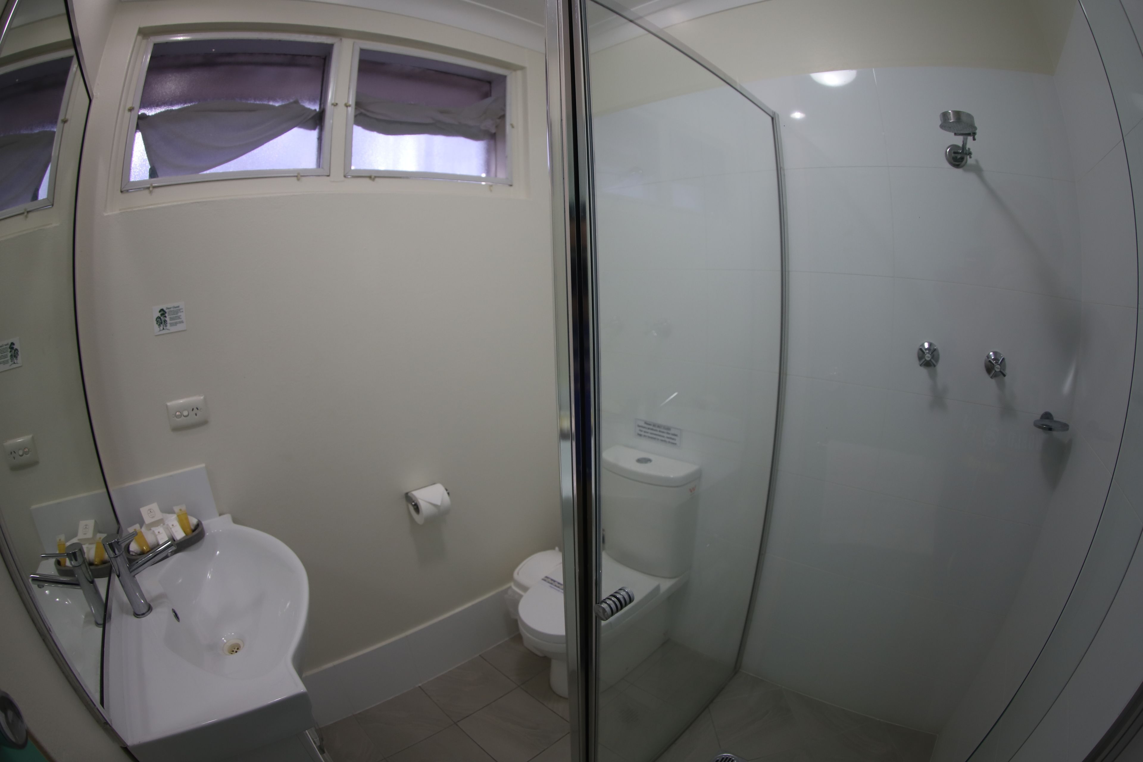 A bathroom with a glass-enclosed shower, a sink, and a toilet.