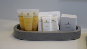A stone basin containing various toiletries including a shower cap, conditioner shampoo, and other personal care items.