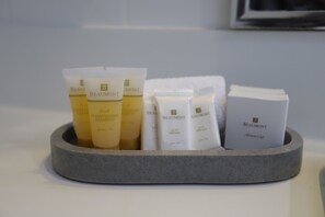 A stone basin containing various toiletries including a shower cap, conditioner shampoo, and other personal care items.