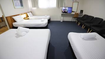 A hotel room with two single beds, a desk with a computer, and a seating area with chairs.