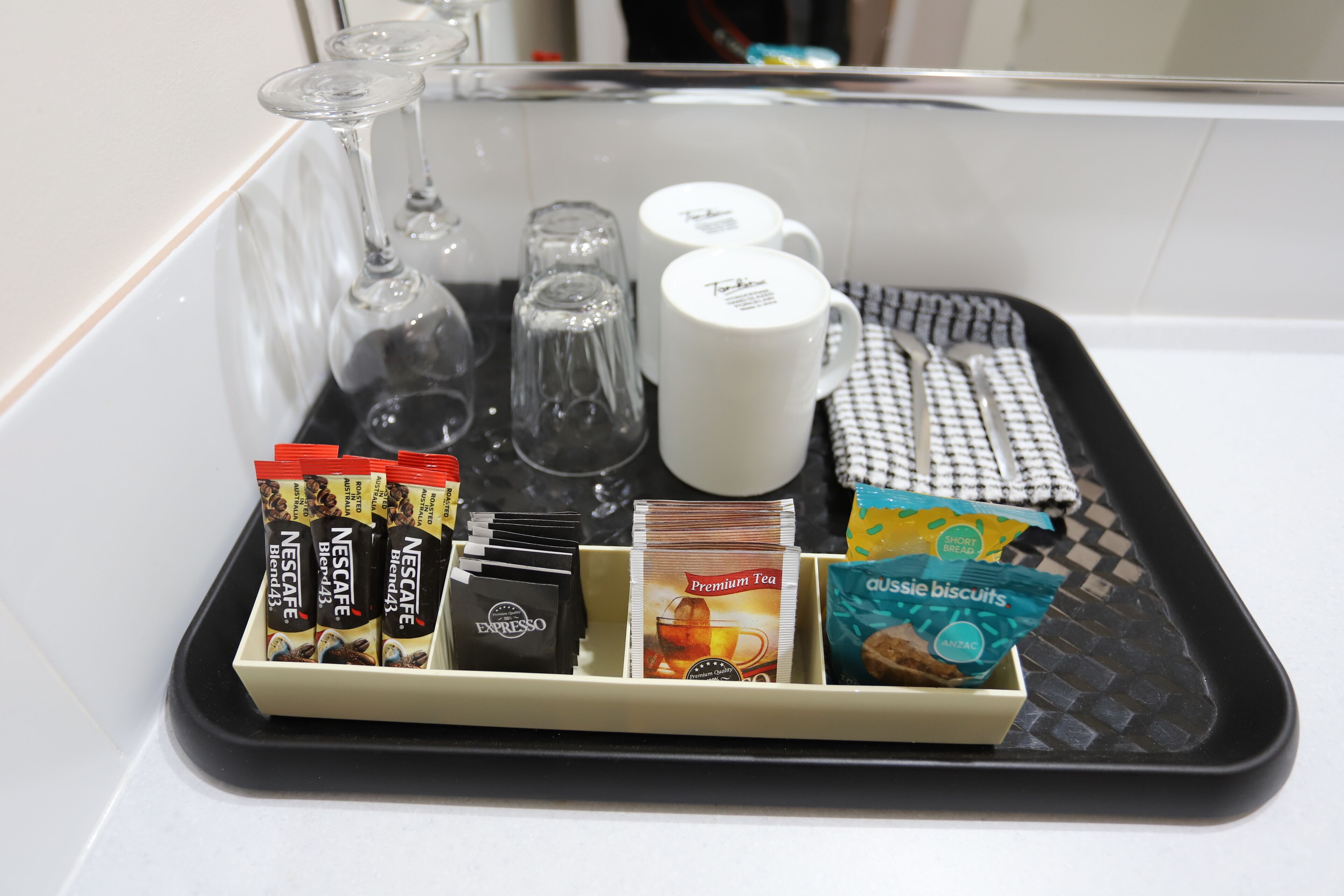 A tray with coffee pods, tea bags, a mug, and a biscuit packet.