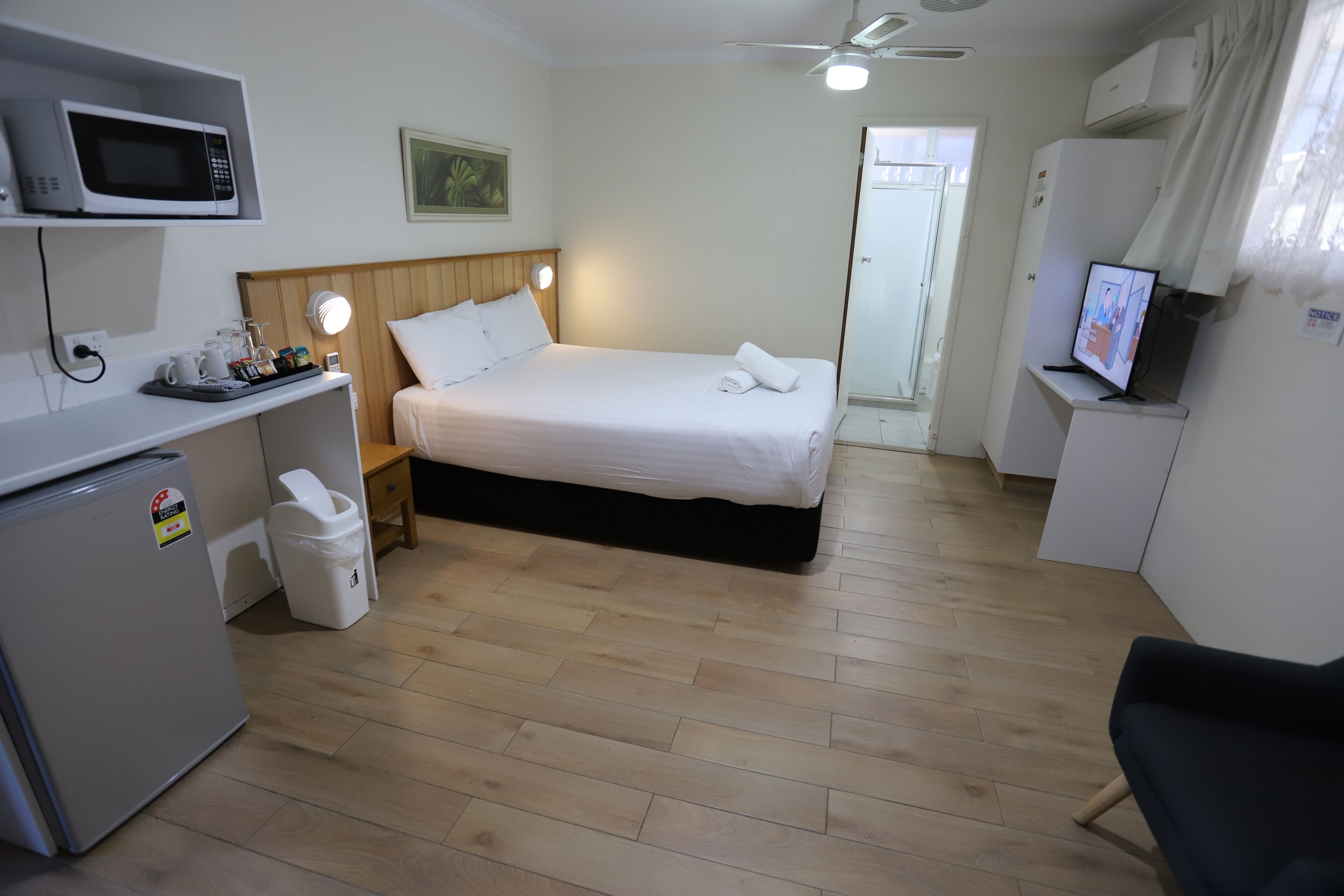 Een hotelkamer met een bed, een bureau met een computer, een magnetron en een koelkast.