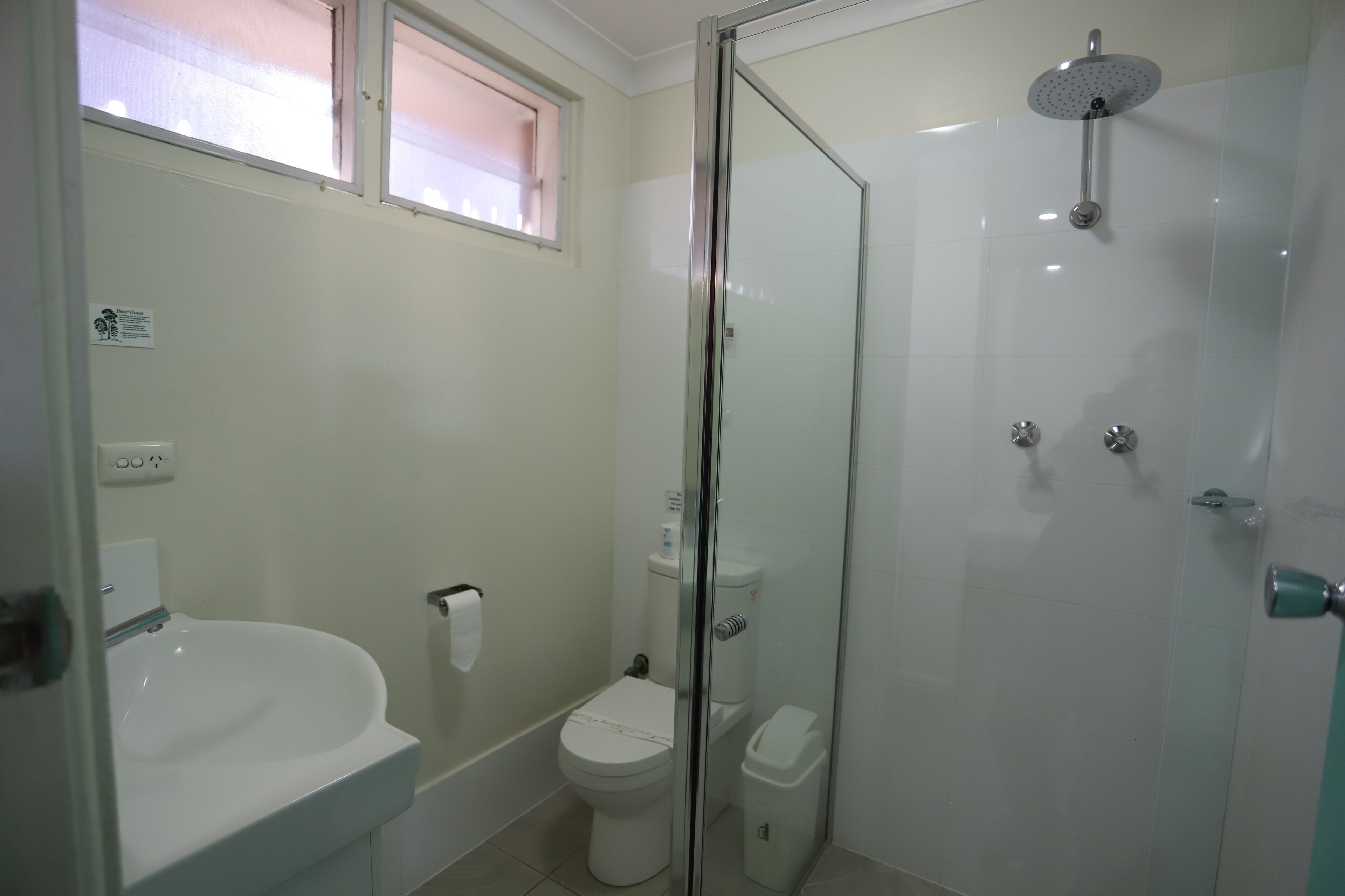 A bathroom with a glass-enclosed shower, a white sink, and a toilet.