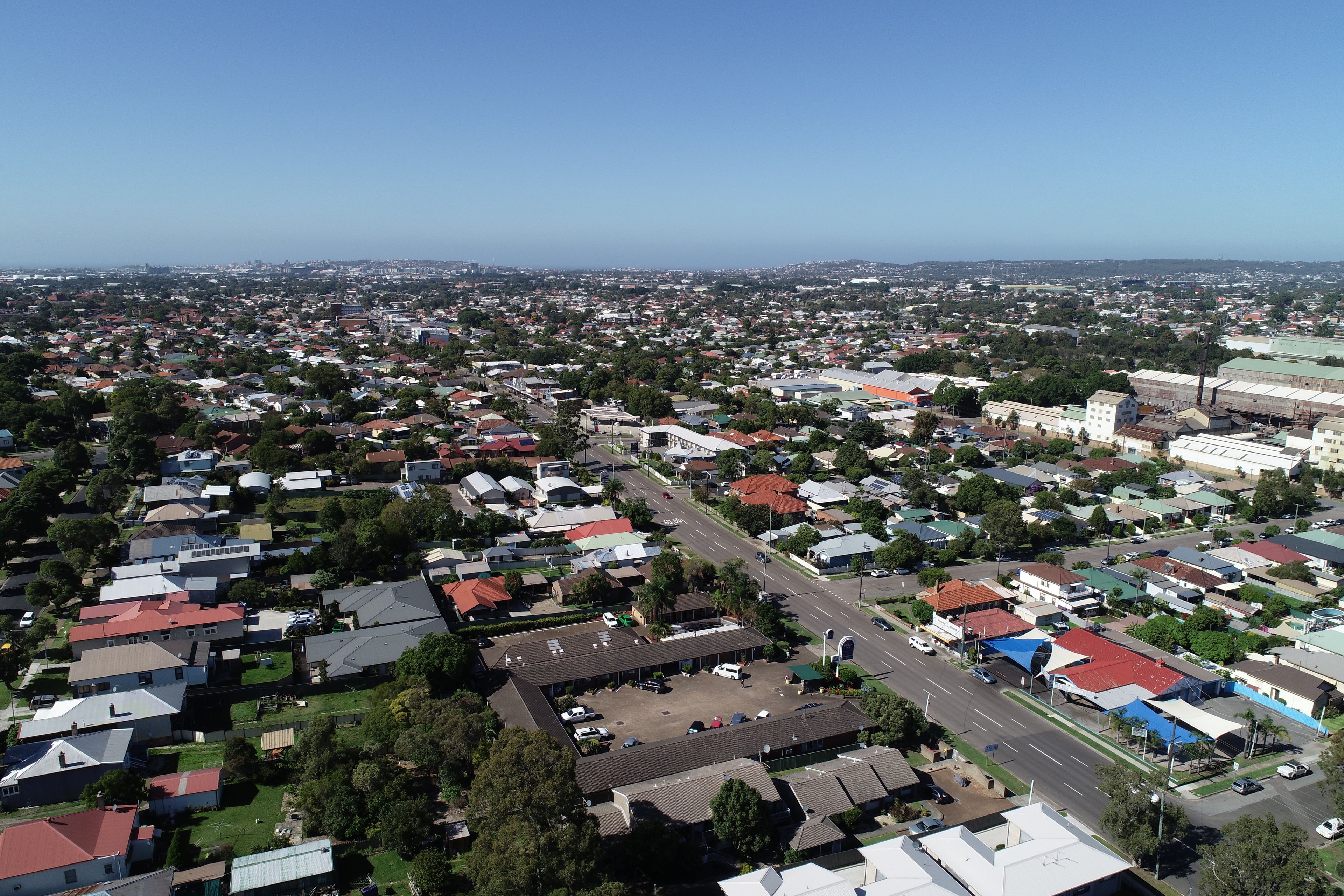 An aerial view of a residential area with houses, roads, and greenery.