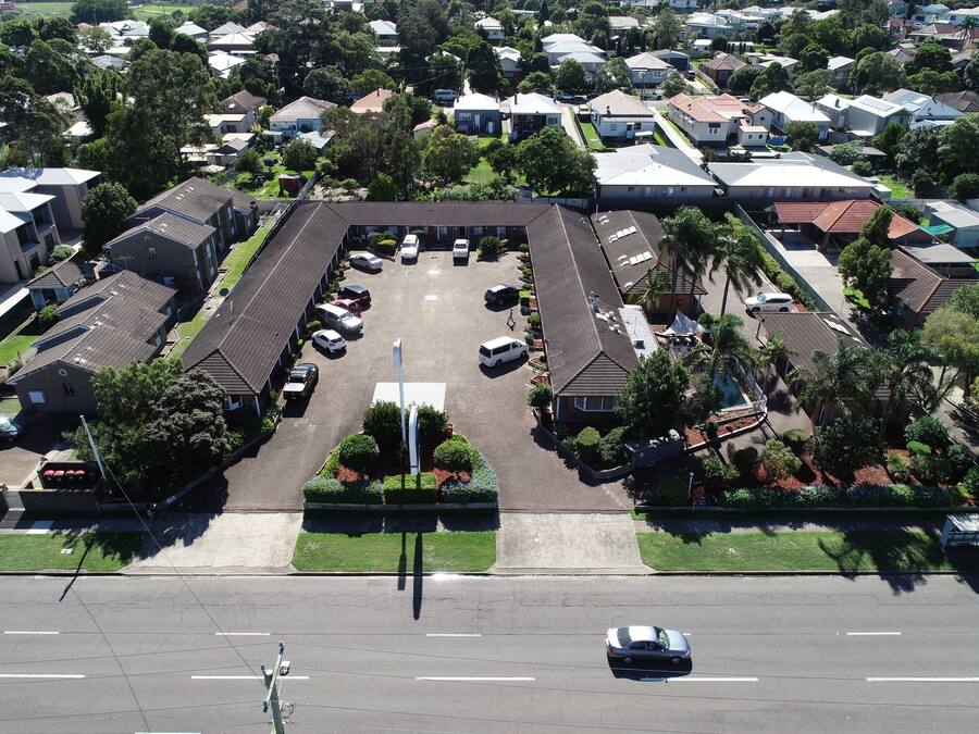 Vista aérea de una zona residencial con un estacionamiento amplio, varias casas y un edificio central de techo plano.
