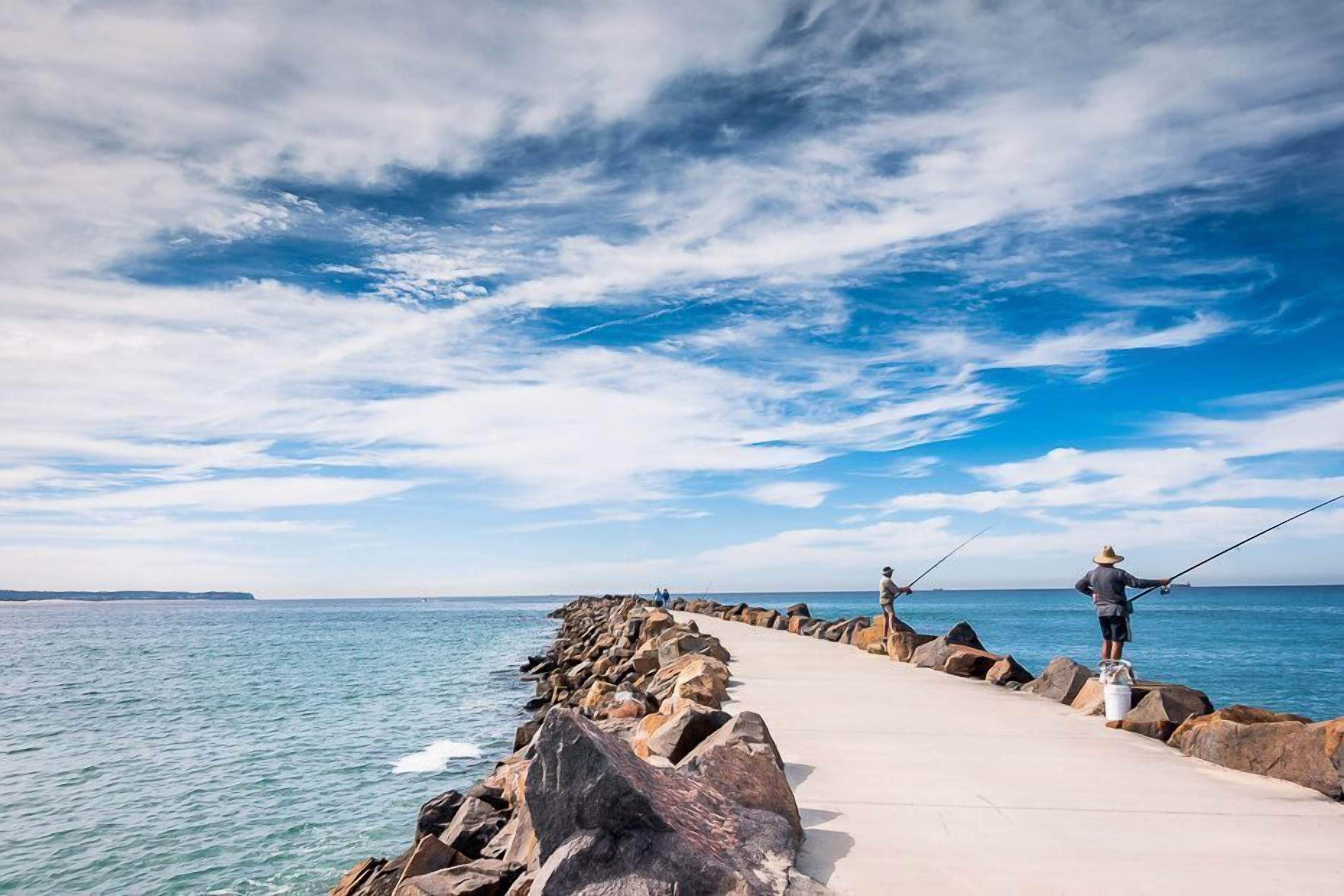 A pier extending into calm waters with a clear sky.