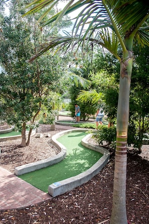 A miniature golf course with a winding path, palm trees, and a well-maintained green surface. - BIG4 Batemans Bay Beach Resort (Batehaven)