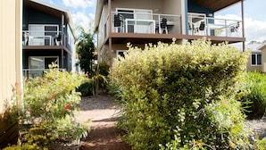 A two-story building with balconies, a paved pathway, and various plants. - BIG4 Batemans Bay Beach Resort (Batehaven)