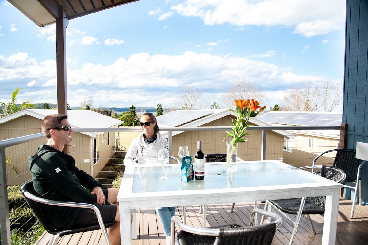 Un patio techado al aire libre con una mesa y sillas, paneles solares en el techo y vistas del paisaje circundante.