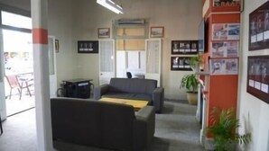A room with a sofa, a small table, a potted plant, and a wall with framed pictures. - Australian Hotel Boonah (Boonah)