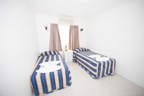 A small, clean room with two single beds, a white nightstand, and a window with curtains. - Ballina Hi Craft Motel (Ballina)