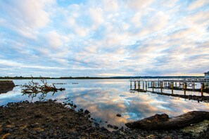 A calm lake with a pier extending into the water, surrounded by rocks and a cloudy sky. - Ballina Hi Craft Motel (Ballina)