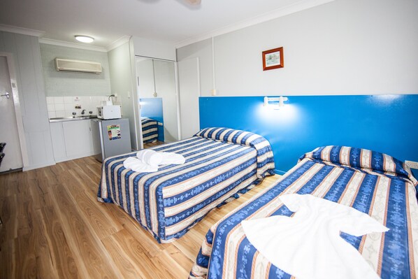 Una habitación de hotel con dos camas, kitchenette y baño.