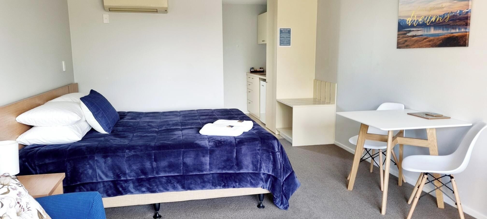 A bedroom with a bed, bedside table, and a desk with a chair.