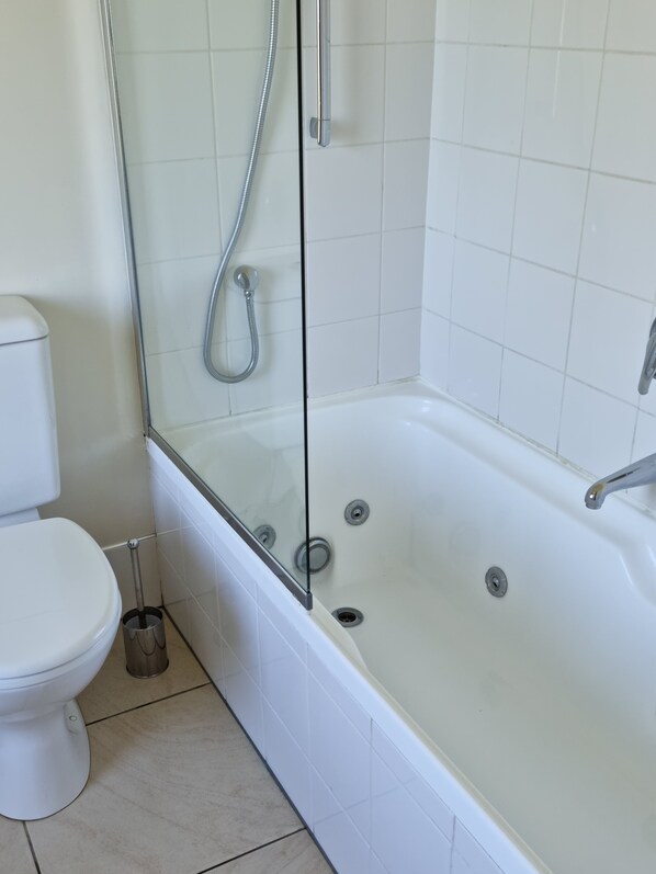 A bathroom with a glass-enclosed shower, a white toilet, and a bathtub. - Methven Motels & Apartments (Methven)