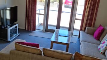 Een woonkamer met een bank, een salontafel en een tv op een dressoir.