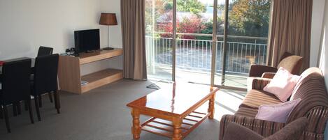Una sala de estar con un sofá, una mesa de centro, un televisor y un escritorio con una lámpara.