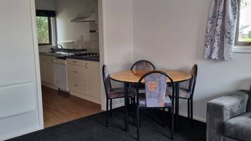 Une cuisine compacte avec un coin repas comprenant une table et des chaises, un canapé et une fenêtre avec des rideaux.