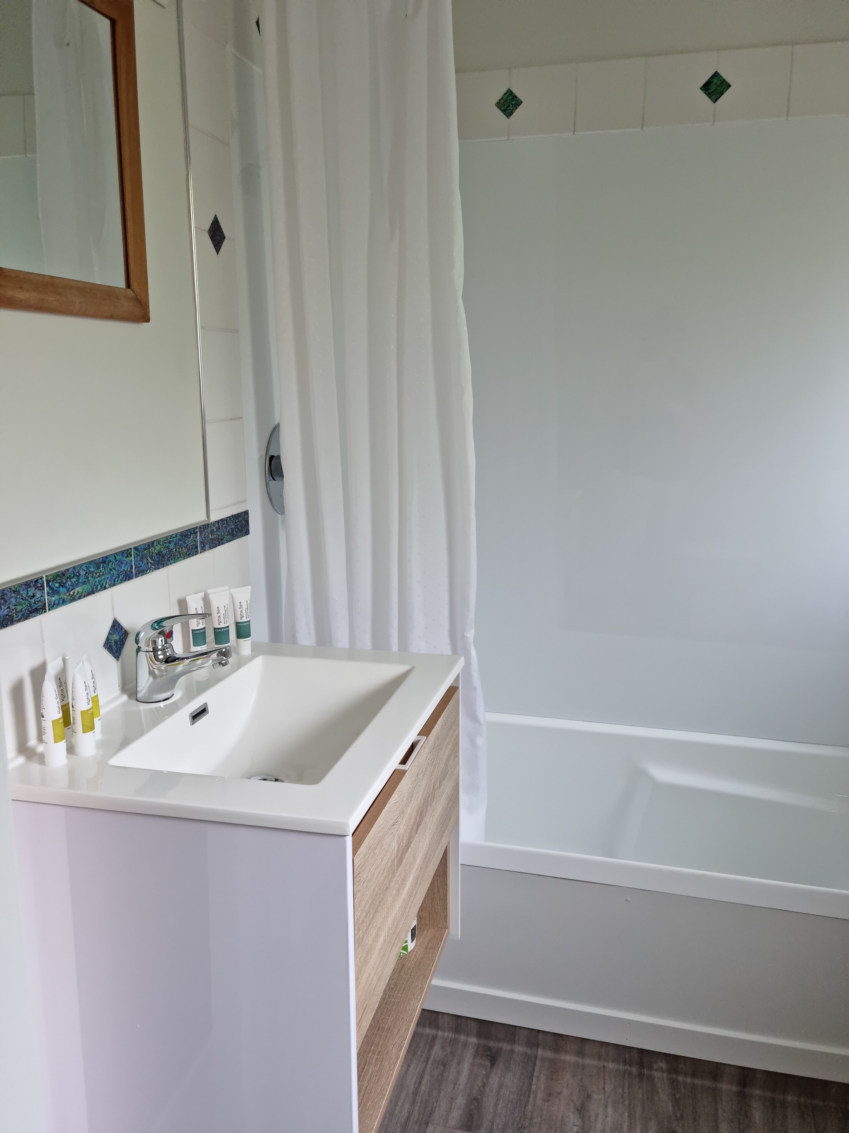 A bathroom with a white sink, mirror, and shower curtain.