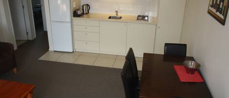 Una cocina compacta con refrigerador, microondas, pileta y comedor con mesa y sillas.