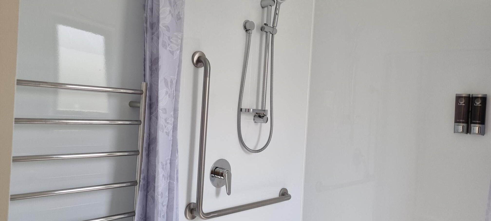 A bathroom with a shower, a towel rack, and a toilet paper holder.