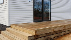 A modern building with a wooden deck and a sliding glass door.