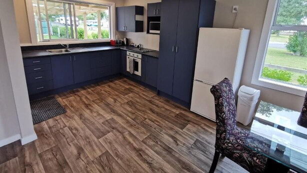 A compact kitchen with dark cabinets, a built-in oven, and a refrigerator.