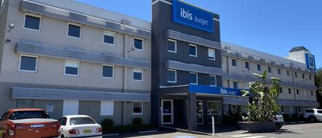 A modern hotel building with a prominent 'ibis budget' sign.
