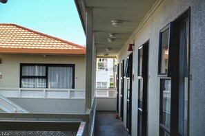A corridor with a tiled roof, a staircase, and a row of windows.