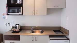A compact kitchenette with a microwave, kettle, and a small sink. - Marksman Motor Inn (Wellington)