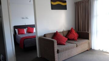 A room with a bed, a sofa, and a painting on the wall.