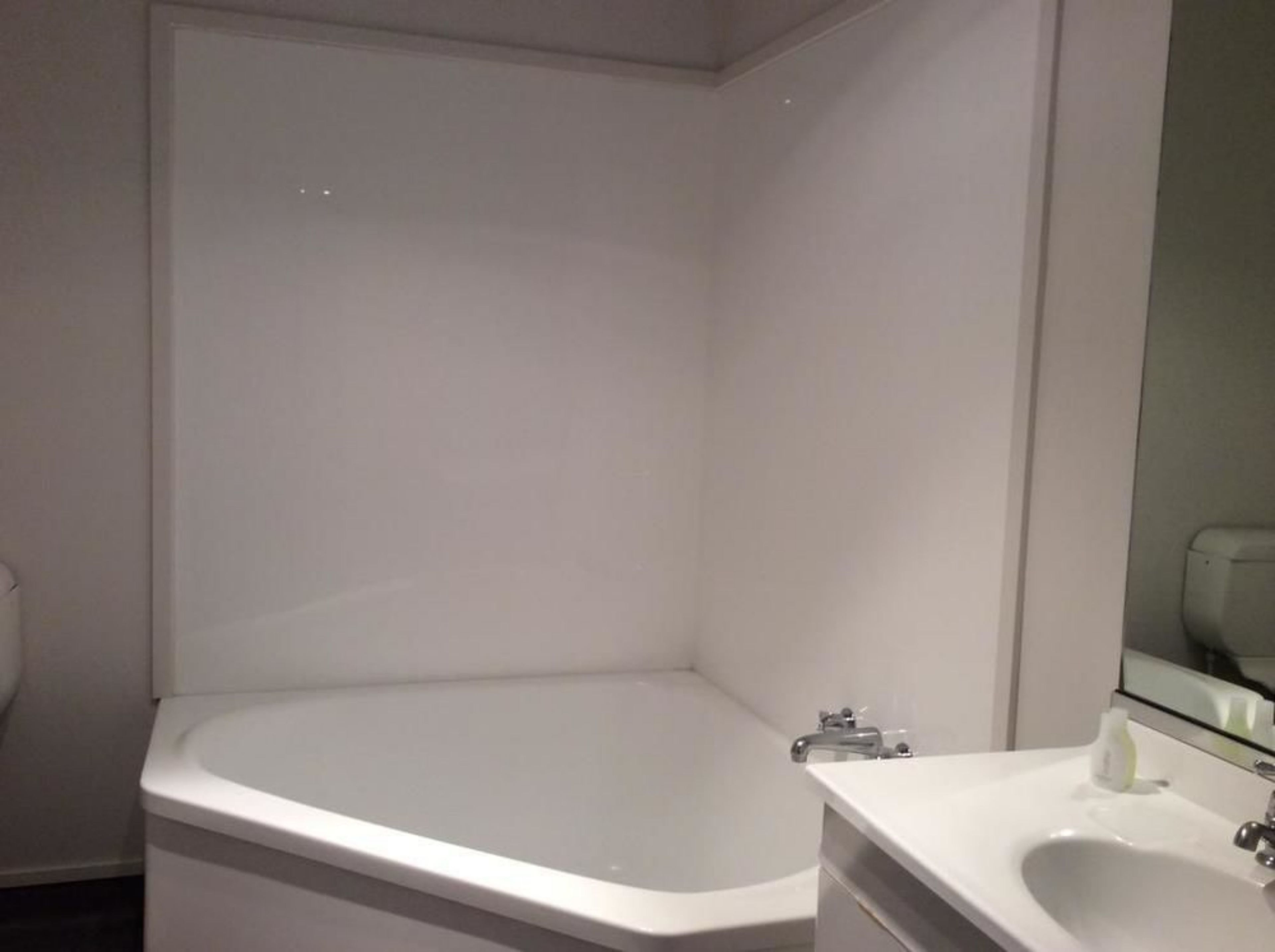 Un baño con una bañera blanca, un lavamanos y un espejo.