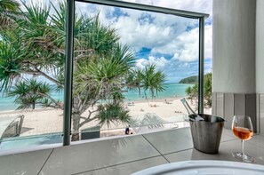 Un balcón con vista a la playa, una copa de vino y un cubo de metal.