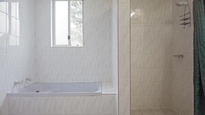 A bathroom with a bathtub, a shower, and a window.