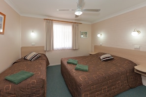 A hotel room with two beds, a ceiling fan, and wall-mounted lights.