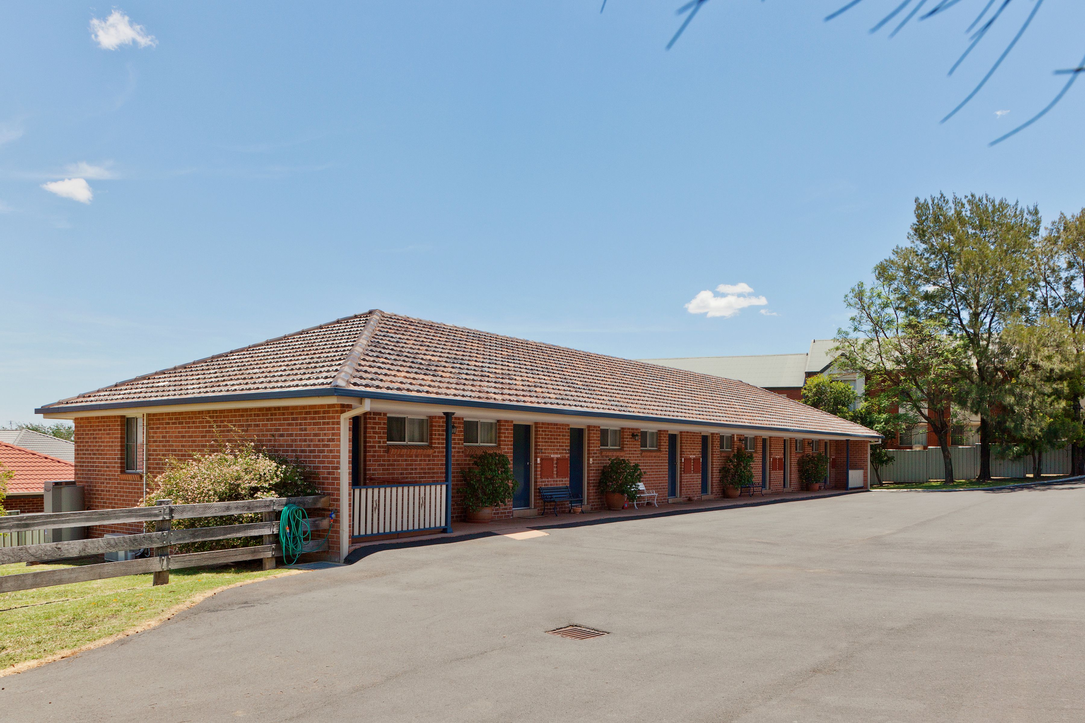 A single-story motel with a tiled roof, a covered parking area, and a small front garden.