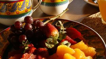 Een tafel met een schaal fruit, theepotten en kopjes.