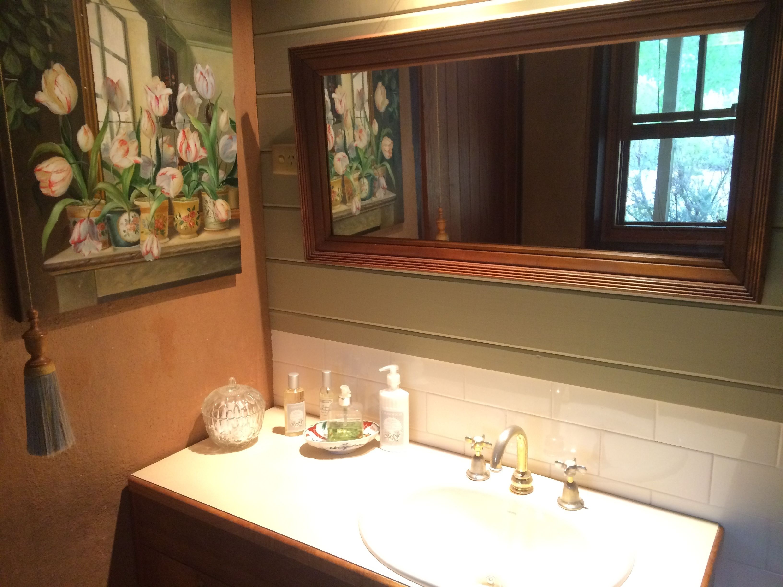 A bathroom with a sink, mirror, and a painting of tulips on the wall.