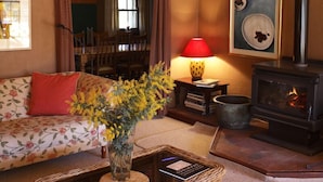 Un salon chaleureux avec un canapé, une cheminée, une lampe et un vase rempli de fleurs.