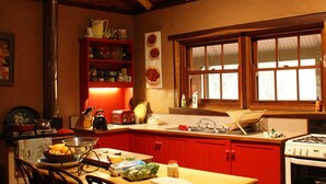 Une cuisine avec des poutres en bois, des meubles de rangement rouges et une table à manger avec des chaises.