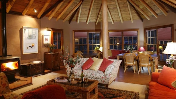 Un salon chaleureux avec une cheminée, des poutres apparentes en bois et des sièges confortables.